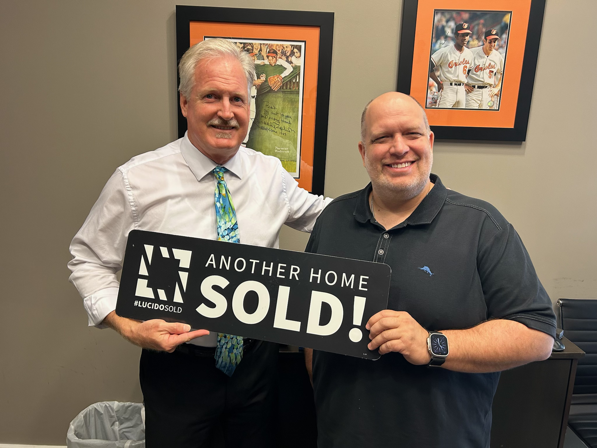 Jim Gladden holding Another Home Sold! sign with happy client
